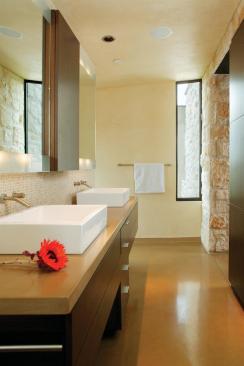 Symmetry plays an important part in this room's sophistication. The medicine cabinet, drawers below, and linen cupboard opposite evenly align. Above the dual square sinks, twin mirrors are sandblasted top and bottom, with lights behind creating an uniform glow.