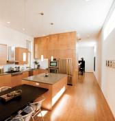 Artificial and natural lighting help articulate spatial connections. Integrated cans march uninterrupted along the ceiling perimeter to emphasize the unity of the primary living spaces. Light cast from a row of pendants showcases the island as a focal poi