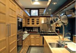 A high-capacity custom pot rack hangs at the same level as the light soffit that rings the kitchen and adjacent nook. De Vido used the lowered scale both hover 7 feet above the floor to give the more personal spaces some intimacy.