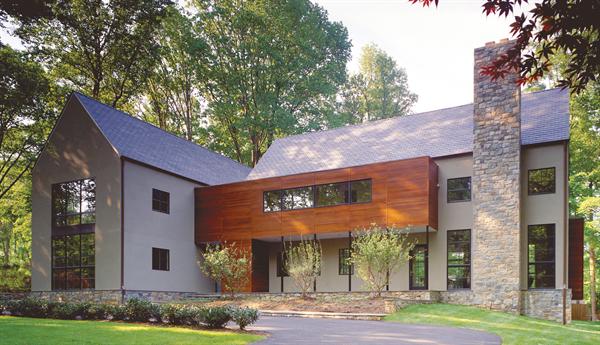 The home's stripped-down gables, muntined windows, and stone landscape walls and chimney establish firm roots in its traditional neighborhood.