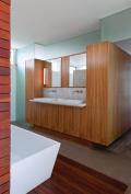 A walnut-surfaced millwork element presents opposite sides to the bath and bedroom.