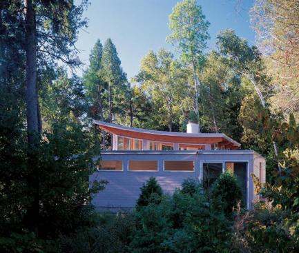 A simple shape, local materials, and sensitive siting ground this weekend home in its wooded lakefront surroundings. A winglike clerestory opens the interior to the sky.