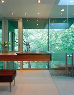 A mirrored wall opposite the shower doubles the appearance of the room's size while also concealing pipes and wires. A large skylight over the shower balances the quality of light spilling through the diaphanous wall.