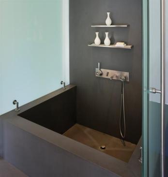Engineered stone forms the floor, tub, and wainscot of this master bath, which doubles as a pool cabana. Sliding glass partitions at the tub yield a variety of possible configurations.
