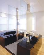 The polished granite vanity and tub surround were kept low to the ground to match the windowsill height and to emphasize the transparent connection to the ceiling.