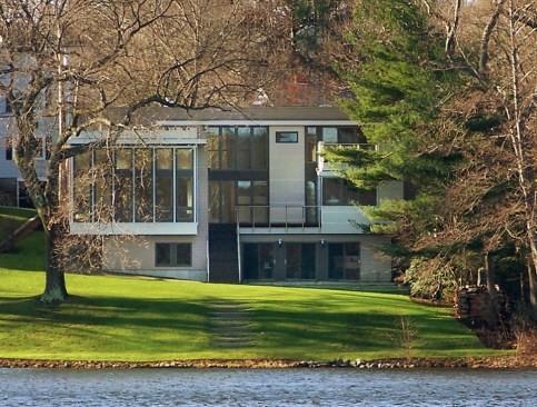 The+house+settles+into+its+lake-side+site%2c+a+collage+of+discrete+volumes+stepping+down+to+the+steeply+sloping+lawn+and+lake.+