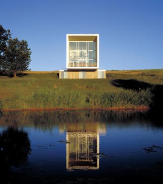 The 24-by-24-foot window wall on the home's large end feeds light into the interior. Standingseam metal (left) provides a sturdy cladding that suits the agricultural context.