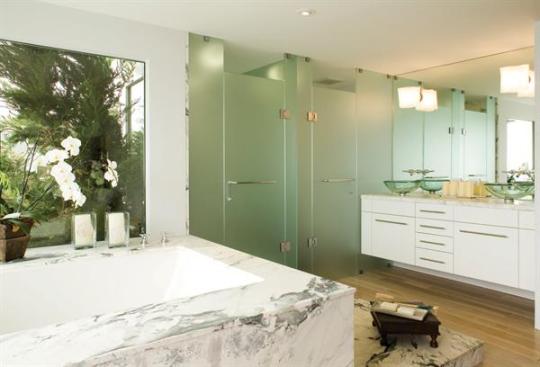 White lacquered custom cabinets are a simple foil to the heavily veined marble. The cantilevered cabinet supports twin vessel sinks. I use a floating vanity pretty often,says architect Mark English, because I like seeing the floor continue.