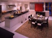 The efficient but well-appointed kitchen hides its utility without blocking views or hindering access to the casual dining area and spaces beyond. A butler's pantry to the left of the refrigerator provides additional storage.