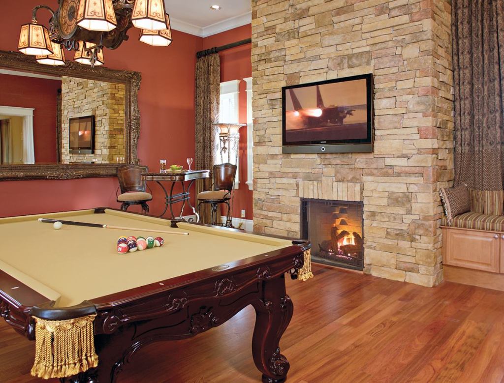 GAME TIME: A flat-panel plasma television and a propane fireplace set into an aggregate flagstone surround (above) provide just one area of entertainment in the game room. A window seat with in-bench storage can be a quiet retreat, while ample access to the loggia and its outdoor kitchen—not to mention a home theater nearby—offers additional options.
