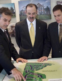 A WORKING PARTNERSHIP: Mid-Atlantic Cos.' three partners (John Lavery, vice president of sales and marketing, Roger Lebbin, and Stephen Paul) pore over a map of one of their Prince George's County, Md., subdivisions displayed in a model home.