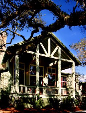 TRUE COLORS: A welcome porch framed with native cypress (opposite page) is unmistakably Southern. The exterior palette of the house was inspired by the moss, lichen, and bark colors of the live oaks.