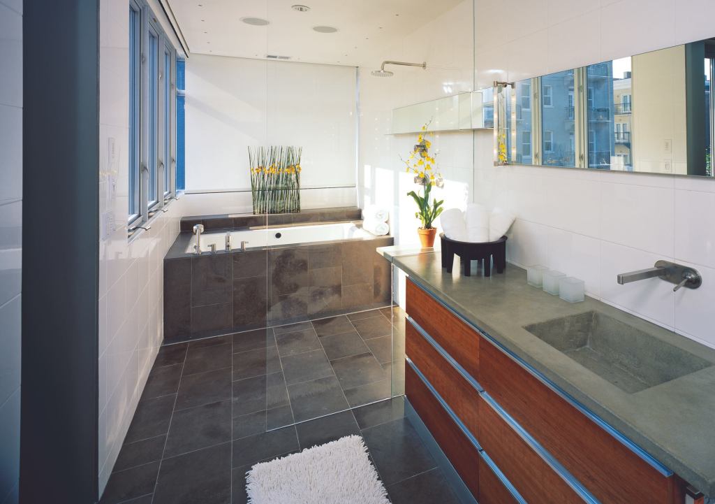 A floating glass-and-copper addition on the second and third stories holds the sleek master bath. A frameless shower door, pierced by the countertop and shaving mirror, marks the point where old and new converge.