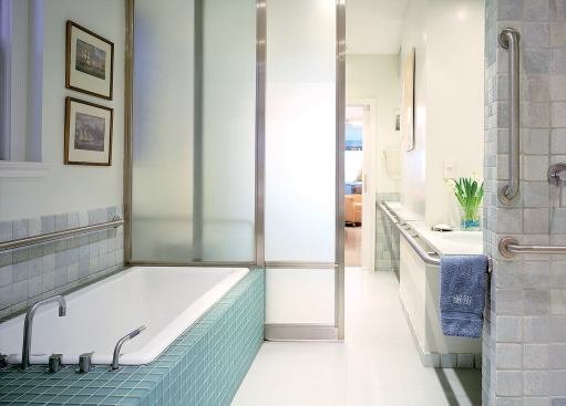 The stainless steel grab rails sparkle in the bright master bath and are emphasized by stainless trim on the glass doors.