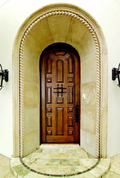 WELCOME HOME: The homes front entry, carved into the elbow of an intimate court, is flanked by stone fountains and wrought-iron lamps. Its splayed stone surround provides a dramatic frame for a 9-foot, hand-carved, knotty alder door.