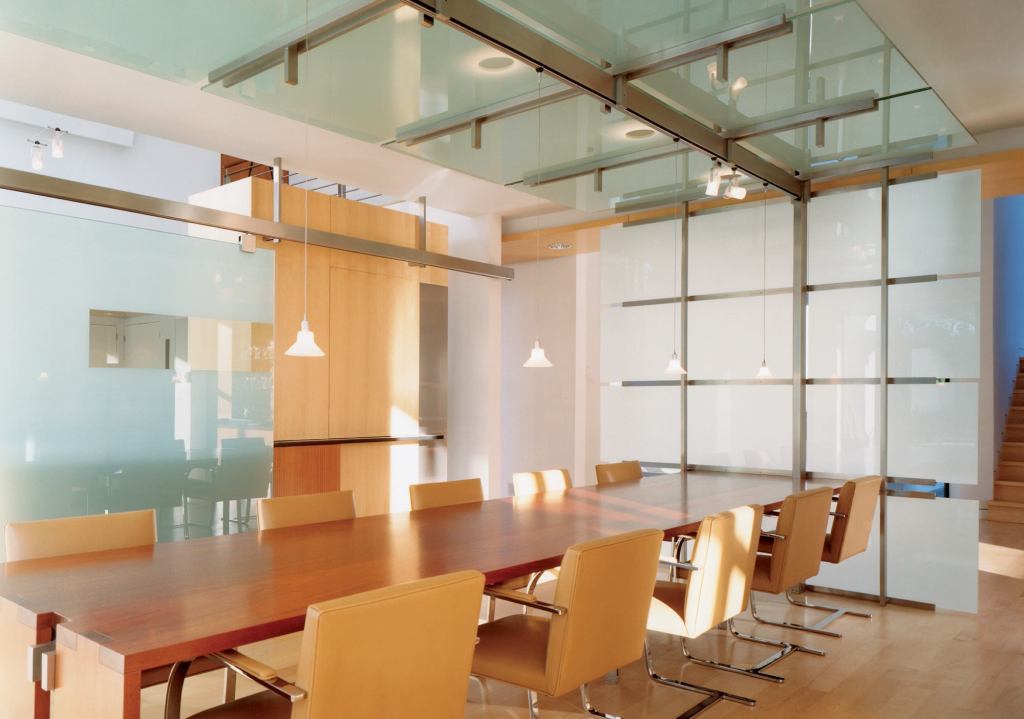 A track lighting system within a metal framework lets owners switch from pendant to track fixtures or back again with ease. Circles cut into the glass make changing overhead bulbs a breeze.