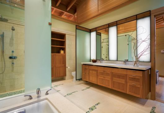 Glass mosaic tiles in shades of blue-green add a touch of color to the limestone floor, the bathtub surround, and the shower floor.