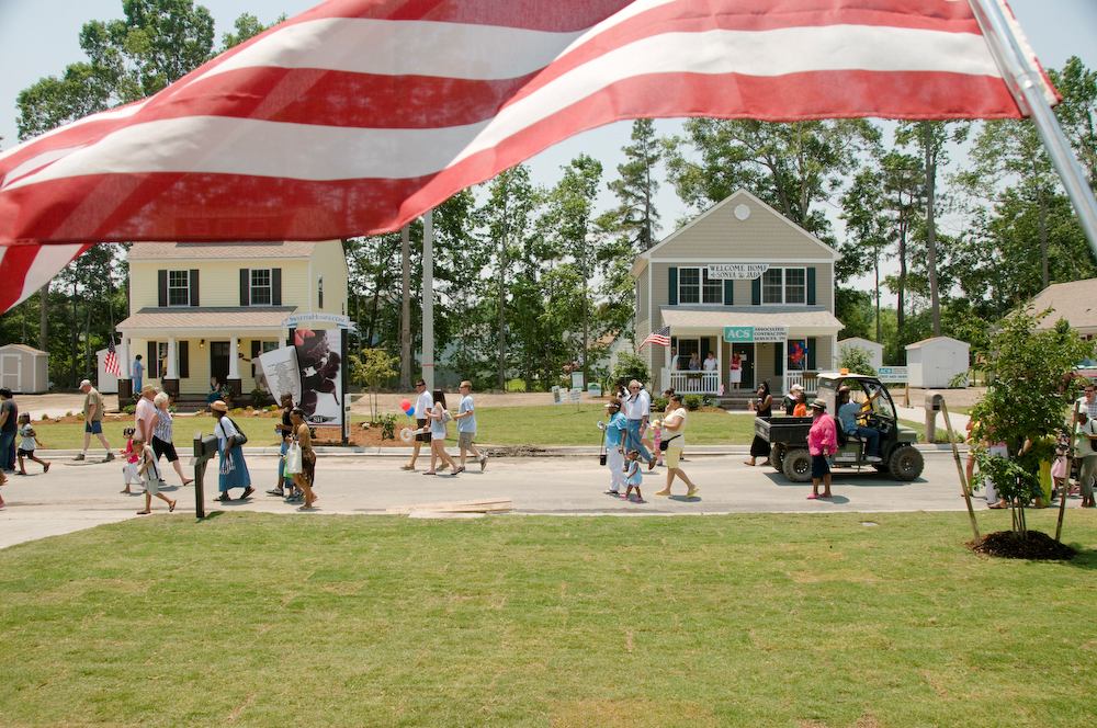A flag waves from the porch of a newly completed Habitat house in Suffolk, Va., as visitors make their way to dedication ceremonies during Home Builders Blitz 2008.