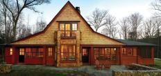 Pretty Face: The lake side of this upstate New York house paints a charming picture for boaters. A strong horizontal band of windows and doors is capped by a dramatic roof gable with wing extensions. “That peak is the toothpick through the club sandwich,” says architect Donald Powers.