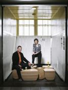 Jeffrey L. Day and E.B. Min post on the Stones Table, which melds organic form with CNC precision. Together, the pieces form a rectangular table.