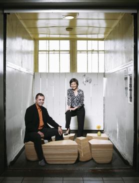 Jeffrey L. Day and E.B. Min post on the Stones Table, which melds organic form with CNC precision. Together, the pieces form a rectangular table.