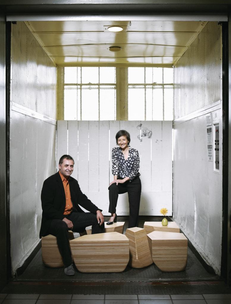 Jeffrey L. Day and E.B. Min post on the Stones Table, which melds organic form with CNC precision. Together, the pieces form a rectangular table.