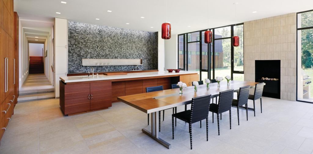 More cook-in dining room than eat-in kitchen, this shared space conceals equipment and food storage behind flush red cedar panels and in stacked cabinets that hide in plain sight.