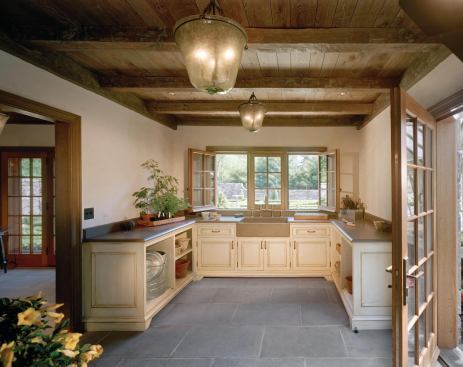 Rough-hewn timber beams and a bluestone floor impart an authentic feeling to this country French-style potting room.