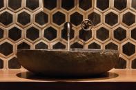 Bold wall tile, a stone sink, and a simple wall-mounted fixture might not work in a bigger or busier bath, but here, they pack a visual punch.