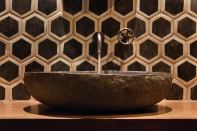 Bold wall tile, a stone sink, and a simple wall-mounted fixture might not work in a bigger or busier bath, but here, they pack a visual punch.