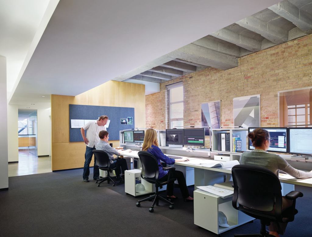 The main entrance to the office is on the third floor. The reception desk is just visible at the back of the space. Behind the wall with the bulletin board is a kitchen area.