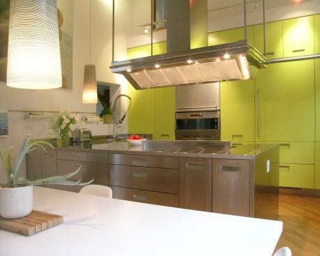 When a Chicago-area home renowned as a significant local example of modern architecture was due for a renovation, it needed to make a statement. To that end, the kitchen was outfitted with a wall of papaya lacquer cabinets and a stainless steel island, providing contrast for the rest of the building’s muted cedar cladding and white interior. Architect: Susan Patenaude, Aaron Wilson, Chicago Builder: Aaron Wilson (renovations), Chicago
