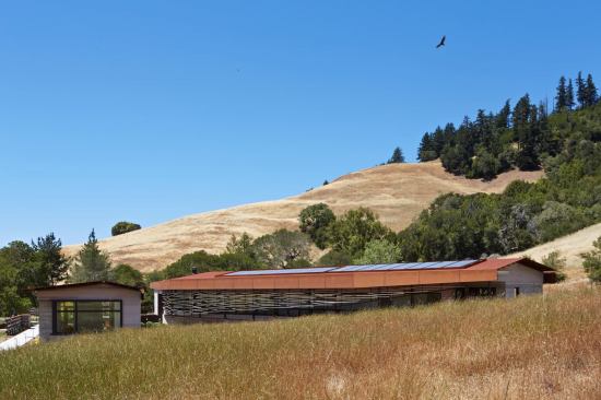 The innovative roof system employs Cor-ten steel roof panels over a continuous ventilation plane and a layer of membrane roofing. A low curb conceals the photovoltaic panels that supply much of the house’s electricity.