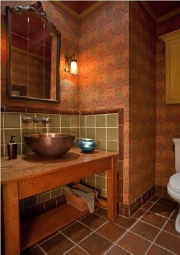 In the powder room, William Morris wallpaper and a vanity of quarter-sawn oak topped by a hammered copper sink forge a perfect union of modern forms and traditional materials.
