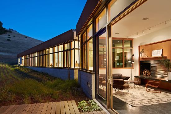 A windowed slot between public and private zones permits adults to gather while maintaining visual access to the children’s play room.