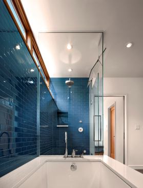 A glass wall of bright blue tiles evokes the original brick of this 20th-century craftsman bungalow’s exterior. The blue hue is calming while bright enough to help early morning bathers wake up, making this master bath a perfect transition space. Architect: Arch 11, Boulder, Colo. Builder: Hammerwell, Boulder