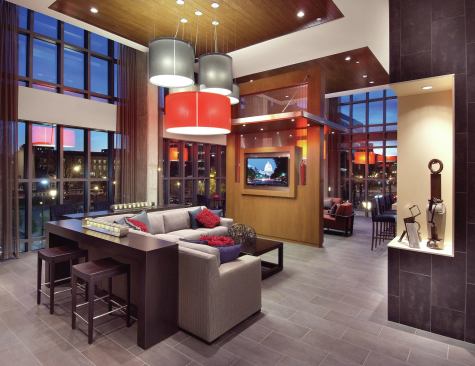 The community's lounge beckons residents to sit and relax with 20-foot-high floor-to-ceiling windows, three flat-screen TVs, and a catering kitchen.