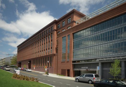 The building's large glass panes and steel joints contrast with the more traditional section of the structure.