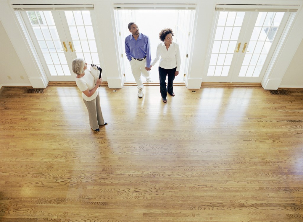 Mature realtor showing couple interior of house, elevated view