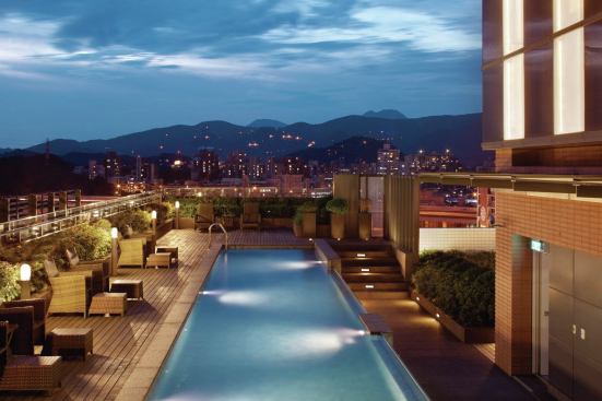A rooftop pool area provides expansive views of the city and the mountains beyond.