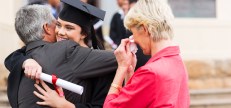 beautiful young female graduate hugging her father at graduation