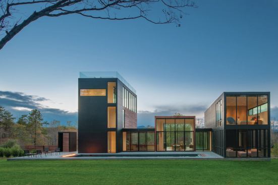 Nestled into a fringe of woodland, the rear of the house opens onto a sparely detailed pool terrace.