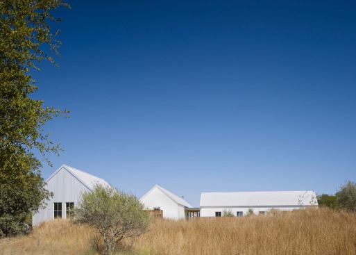 Small, taut volumes are clad in white metal and composite siding that complements the land’s golden grasses.