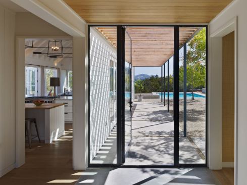 The glass and steel entry is a bridge between the public and private parts of the house. A bedroom wing is to the right; straight ahead is the pool and courtyard.