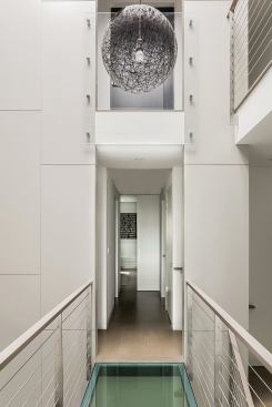 A glass bridge spans the atrium at the apartment’s second floor.