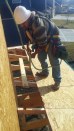 On a Summit Custom Homes jobsite, a framing carpenter wears a safety harness secured to a point above him while working on the roof. He is wearing a hardhat and shoes that have good traction for the slope of the
roof.  