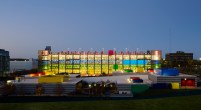 A view from Car Park 4 looking north to Car Park 3.  The color, lighting and cellular qualities create a playful and distinctive lighted sculpture on the campus.  The childcare center is in the foreground