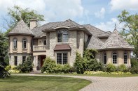 Luxury stone home with turret and cedar shake roof.