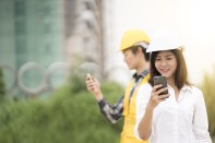 Young asian architect engineer and worker used mobile on working site.