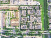 Aerial view of typical multi-level townhome apartment building with swimming pool, surrounded by green garden and rows of cars in parking lots near a business district in Houston, Texas, US.